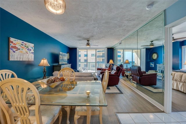 dining space featuring ceiling fan, a wall of windows, a textured ceiling, and light hardwood / wood-style flooring