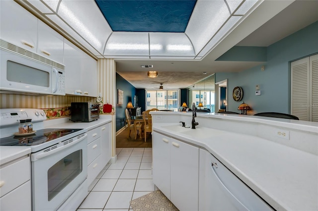 kitchen featuring white appliances, a raised ceiling, white cabinets, and light tile patterned flooring