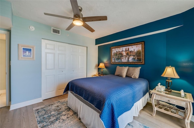 bedroom with ceiling fan, light hardwood / wood-style floors, and a closet