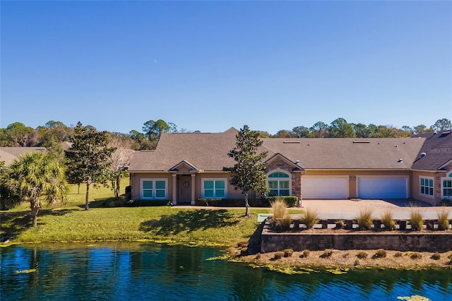 ranch-style home featuring a garage, a water view, and a front lawn