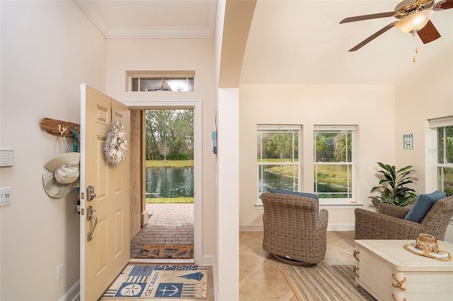 foyer entrance featuring crown molding, a water view, a healthy amount of sunlight, and light tile patterned flooring