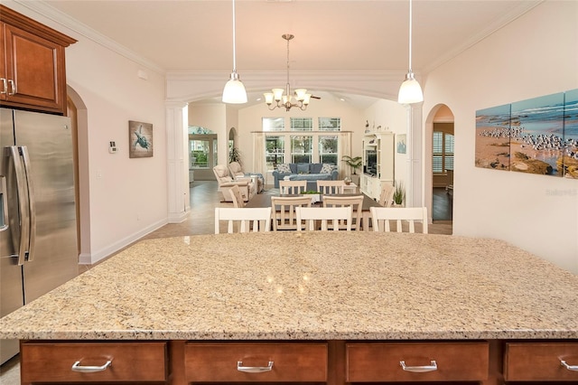 kitchen featuring light stone countertops, pendant lighting, and stainless steel fridge with ice dispenser