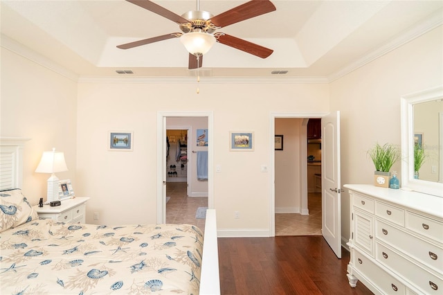 bedroom with a raised ceiling, ornamental molding, and dark wood-type flooring