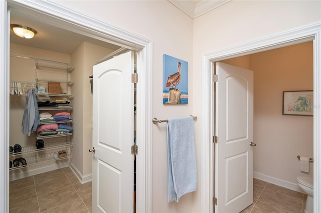 bathroom featuring tile patterned flooring, crown molding, and toilet