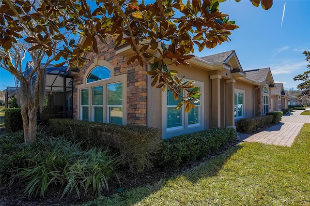 view of side of home featuring a lanai and a lawn