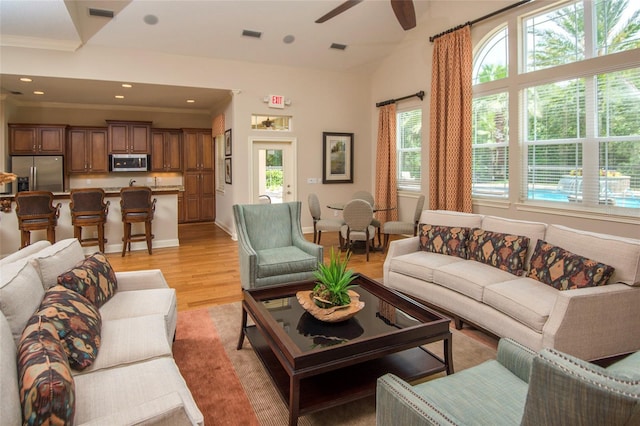 living room featuring ceiling fan, ornamental molding, light hardwood / wood-style floors, and lofted ceiling