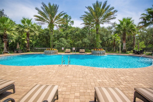 view of swimming pool featuring pool water feature, a hot tub, and a patio area