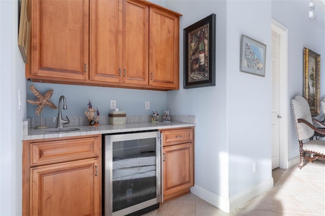 bar featuring baseboards, wine cooler, a sink, indoor wet bar, and light tile patterned flooring