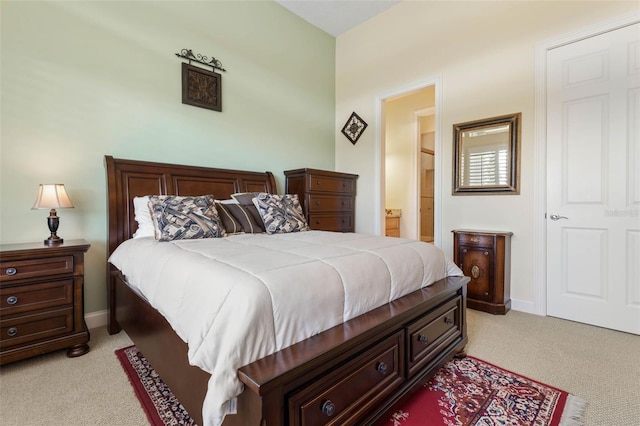 bedroom with light carpet, ensuite bath, and baseboards