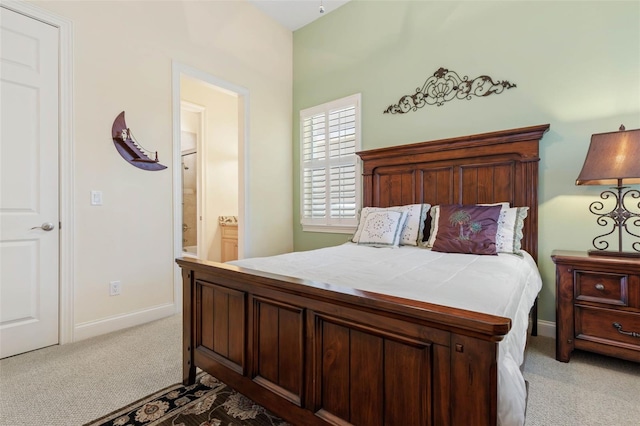 bedroom with light colored carpet, baseboards, and ensuite bathroom