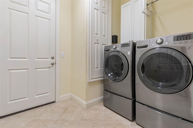 clothes washing area featuring washer and dryer, cabinet space, baseboards, and light tile patterned floors