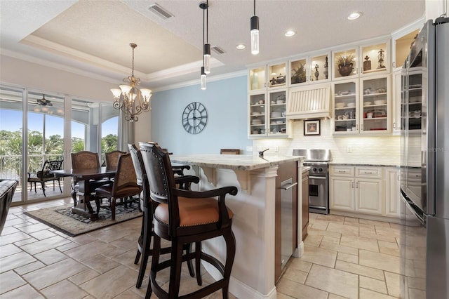 kitchen with visible vents, decorative backsplash, appliances with stainless steel finishes, light stone counters, and a tray ceiling