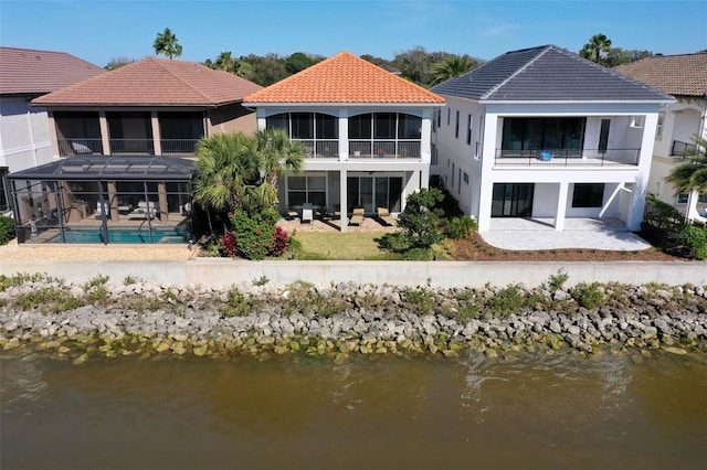 rear view of property featuring a patio area, a water view, a balcony, and stucco siding