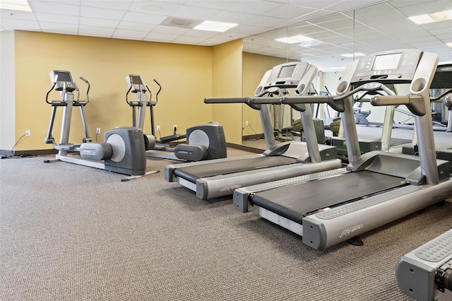 gym featuring a drop ceiling and baseboards