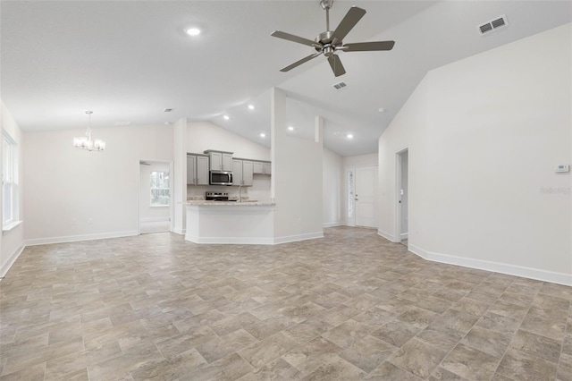 unfurnished living room with ceiling fan with notable chandelier and vaulted ceiling