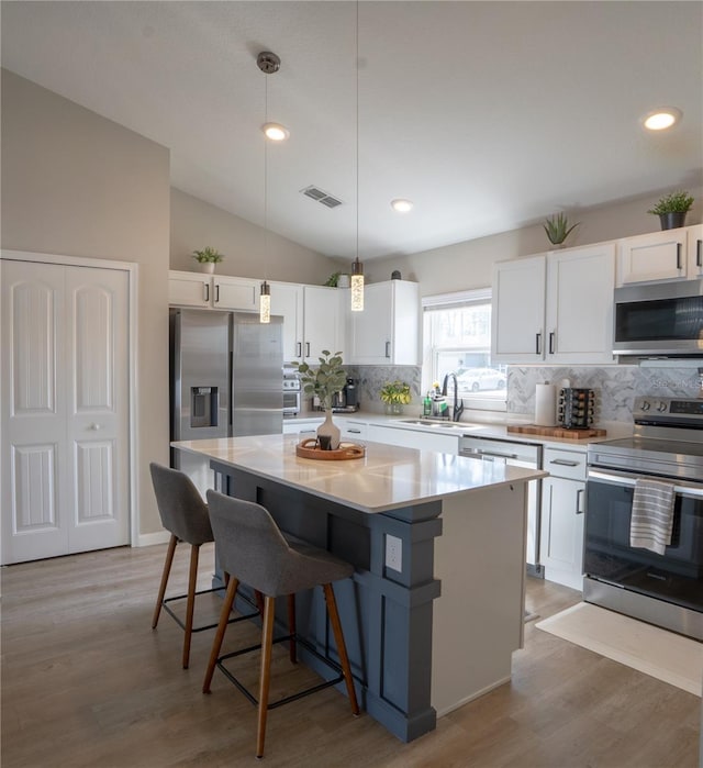 kitchen with a kitchen island, pendant lighting, white cabinetry, sink, and stainless steel appliances