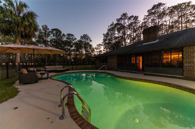 pool at dusk with an outdoor hangout area and a patio