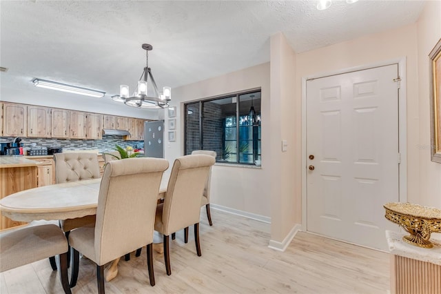 dining area with a notable chandelier, light hardwood / wood-style flooring, and a textured ceiling