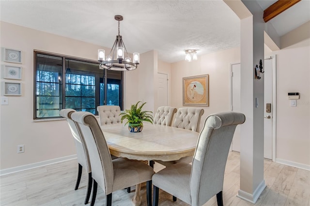 dining area featuring an inviting chandelier, a textured ceiling, and light wood-type flooring