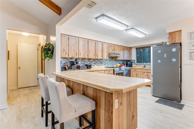 kitchen featuring a breakfast bar, tasteful backsplash, light brown cabinets, kitchen peninsula, and stainless steel appliances