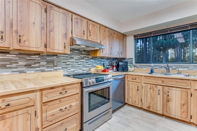 kitchen featuring sink, stainless steel appliances, a textured ceiling, decorative backsplash, and light wood-type flooring