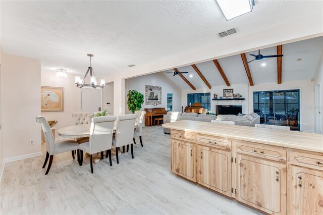 kitchen featuring pendant lighting, ceiling fan with notable chandelier, lofted ceiling with beams, and light brown cabinets