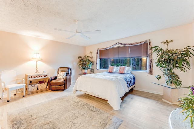 bedroom featuring ceiling fan, hardwood / wood-style floors, and a textured ceiling