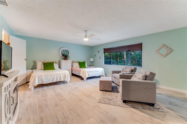 bedroom with ceiling fan, light hardwood / wood-style floors, and a textured ceiling