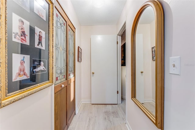 hall featuring a textured ceiling and light hardwood / wood-style flooring