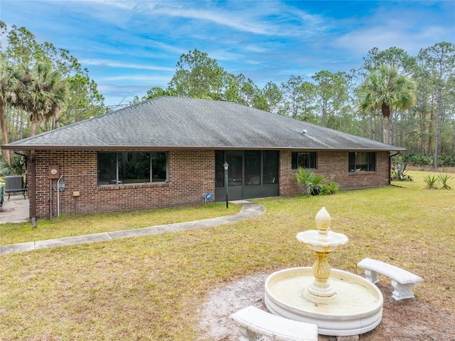 ranch-style home featuring central AC unit, a front yard, and a sunroom