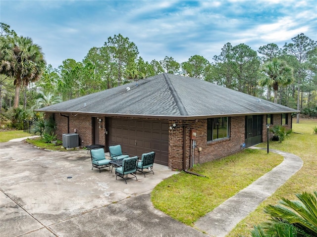 view of side of home featuring central AC unit, a garage, and a yard