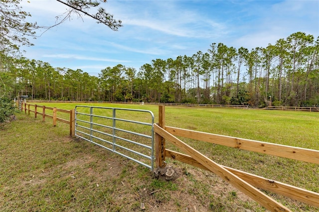 view of gate with a rural view and a yard