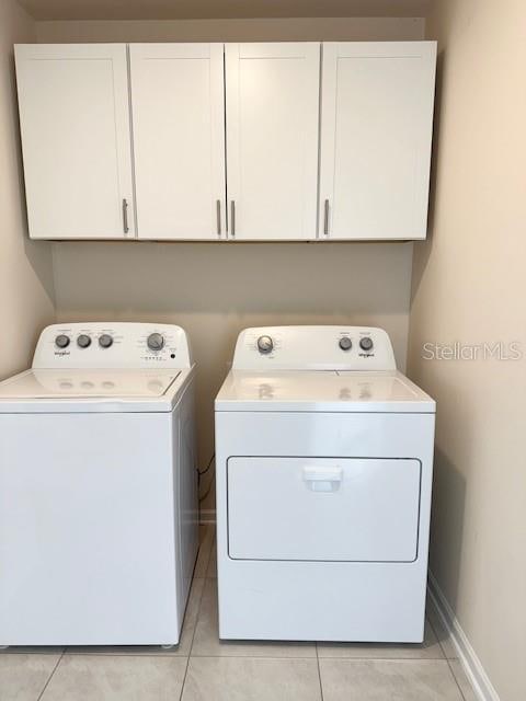 washroom featuring light tile patterned flooring, cabinets, and washing machine and dryer