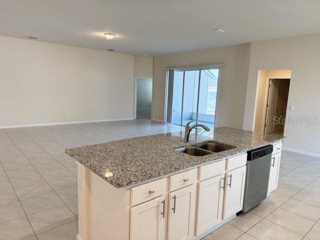 kitchen featuring sink, white cabinets, stainless steel dishwasher, light stone counters, and a center island with sink