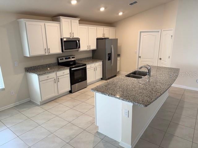 kitchen featuring vaulted ceiling, appliances with stainless steel finishes, sink, white cabinets, and dark stone counters