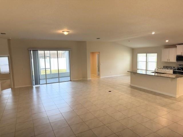 unfurnished living room with a healthy amount of sunlight, sink, and light tile patterned floors