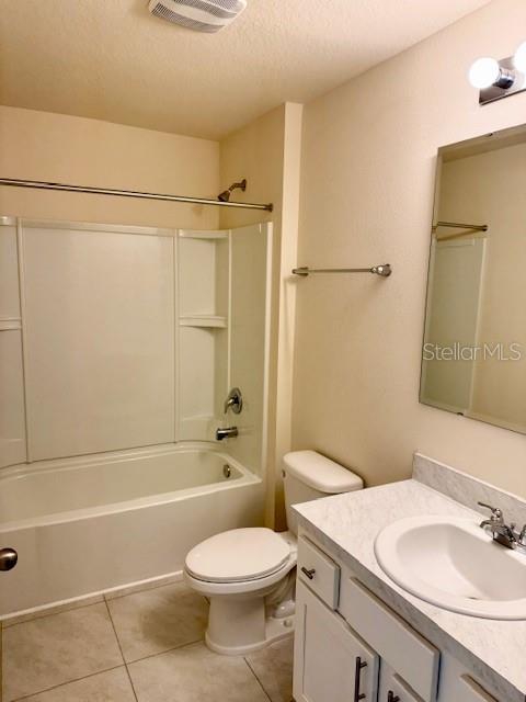 full bathroom featuring shower / bath combination, vanity, toilet, tile patterned floors, and a textured ceiling