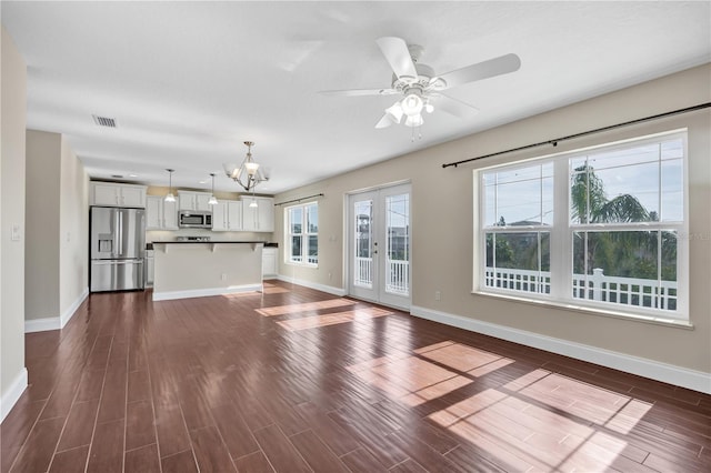 unfurnished living room with dark hardwood / wood-style flooring, ceiling fan with notable chandelier, and french doors