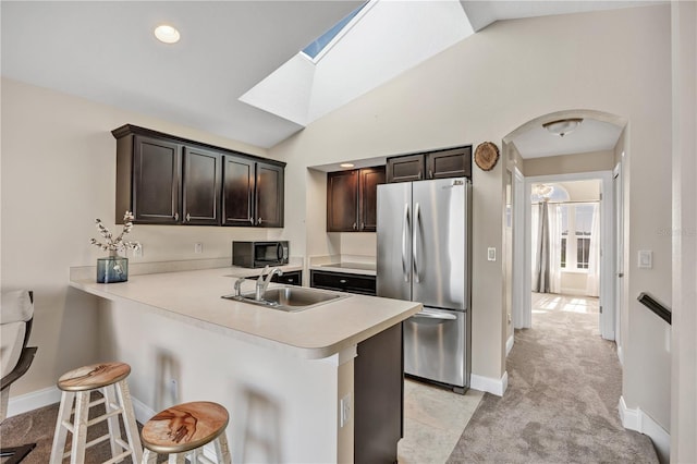 kitchen with stainless steel refrigerator, a breakfast bar, kitchen peninsula, and sink