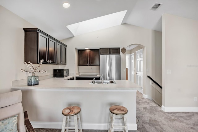 kitchen with sink, stainless steel fridge, a breakfast bar area, and kitchen peninsula