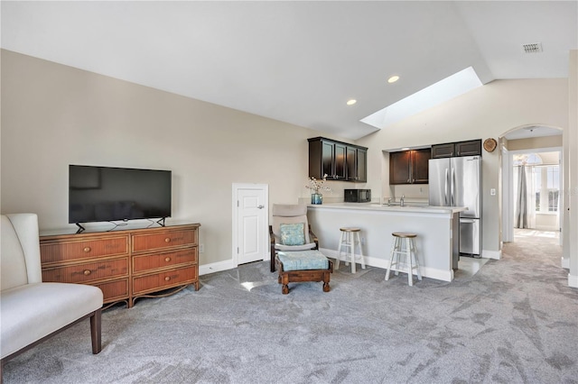 living room with lofted ceiling with skylight, sink, and light carpet