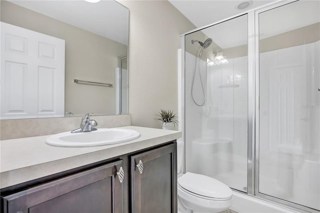 bathroom with vanity, toilet, and a shower with shower door