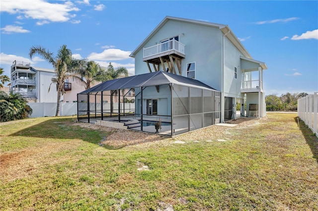 rear view of property with a balcony, a lanai, and a yard