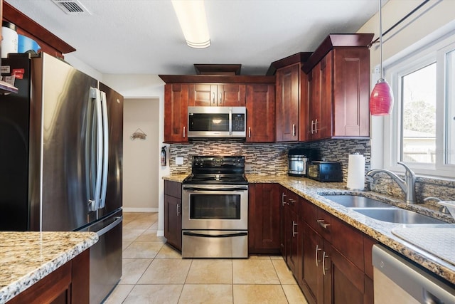 kitchen with appliances with stainless steel finishes, pendant lighting, sink, backsplash, and light tile patterned floors