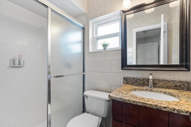 bathroom with walk in shower, vanity, toilet, and tile walls