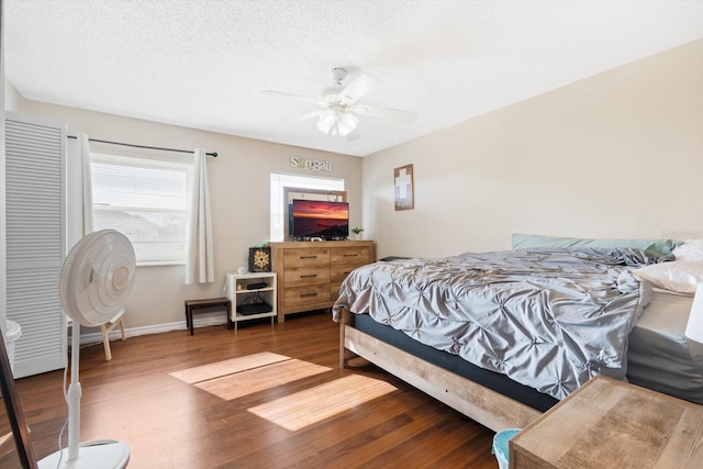 bedroom with ceiling fan, dark hardwood / wood-style floors, and a textured ceiling