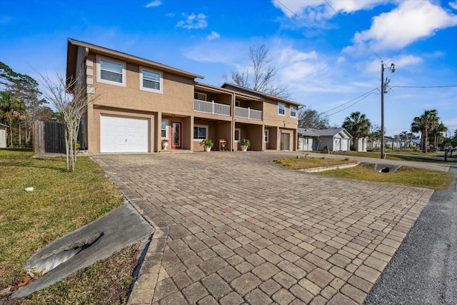 view of front property featuring a garage, a balcony, and a front yard