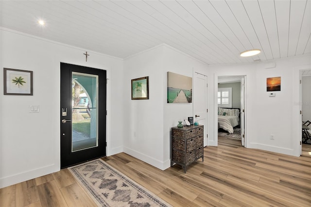 entryway featuring crown molding, light wood finished floors, wooden ceiling, and baseboards