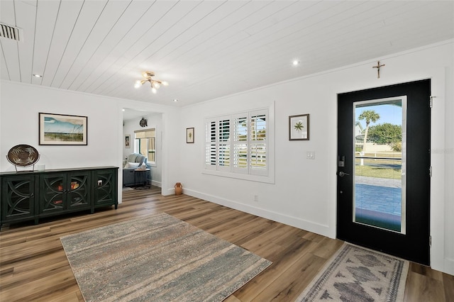 entrance foyer featuring visible vents, baseboards, wooden ceiling, ornamental molding, and light wood-style floors