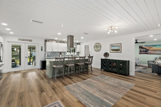 kitchen featuring light hardwood / wood-style flooring, a breakfast bar, island exhaust hood, white cabinets, and a kitchen island